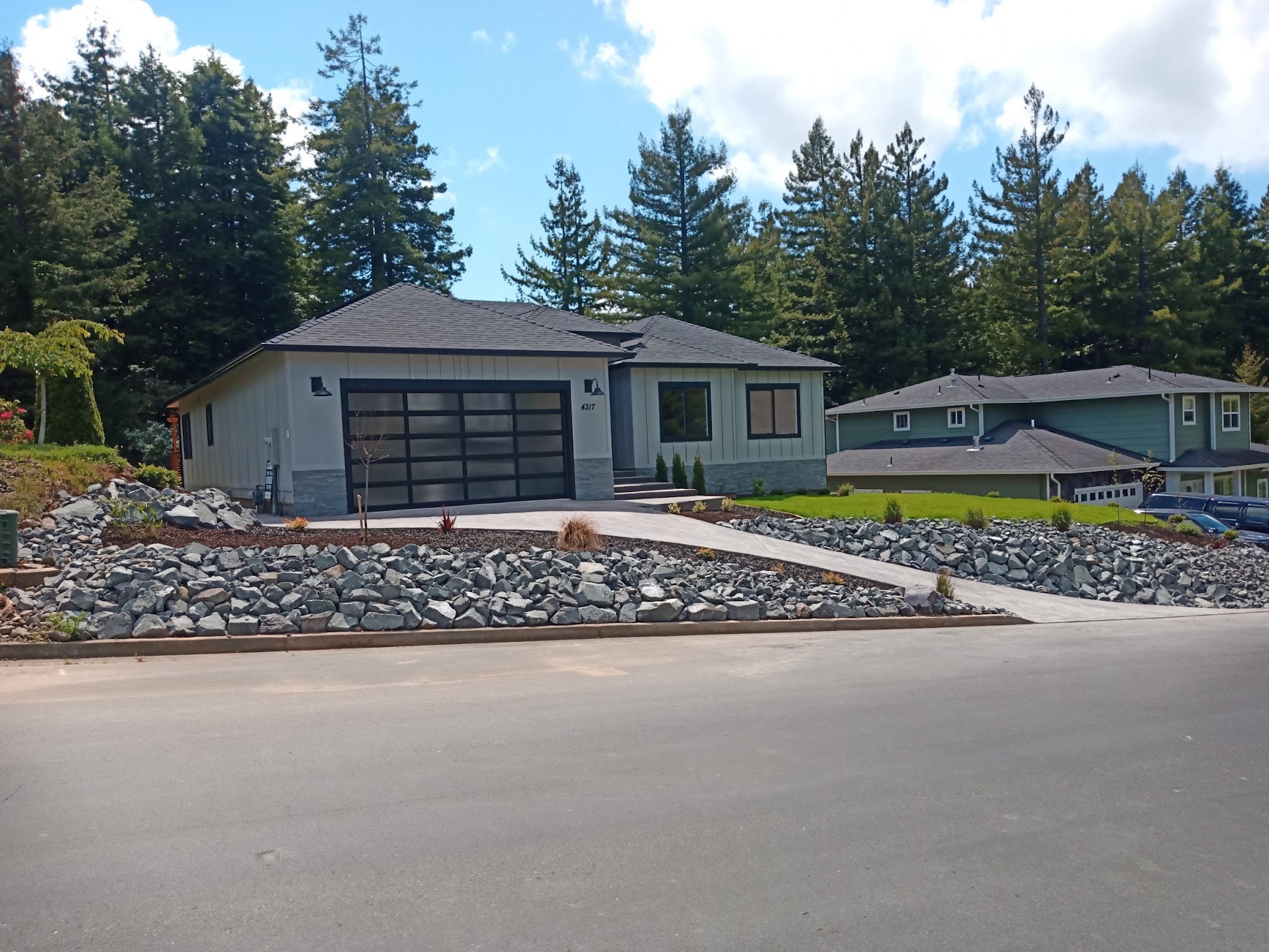 Finished single-story custom home with stone accents and glass-panel garage door